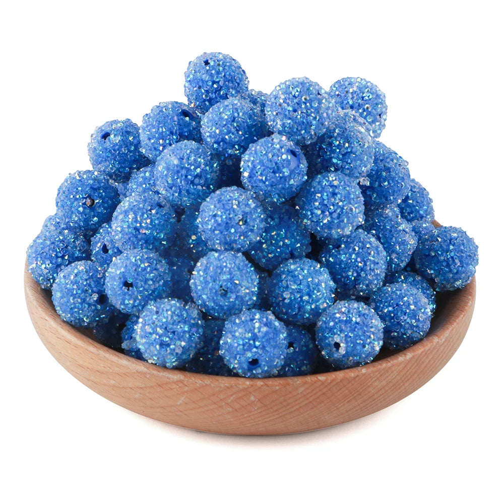 A pile of bright blue textured resin beads for jewelry making in a wooden bowl.