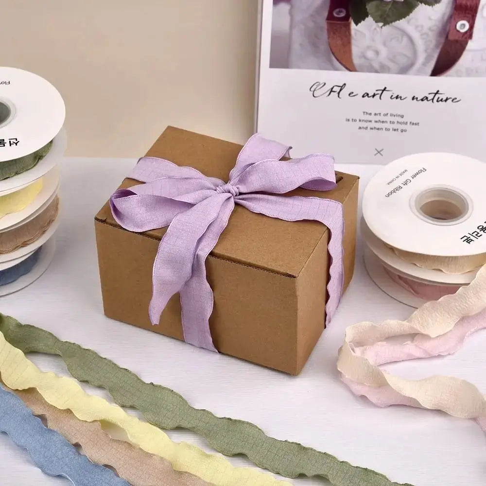 A gift box of purple yarn ribbon with various colored yarns laid out on a white surface.