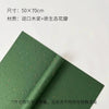 A sheet of dark green decorative packaging paper with dried flower petals rolled up.