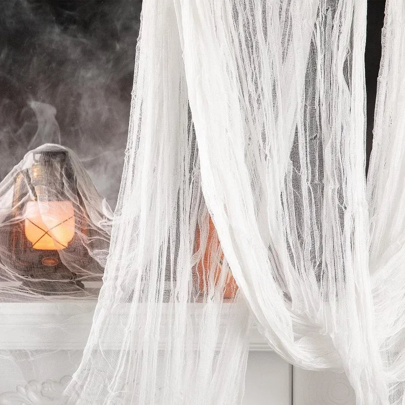 Black creepy gauze cloth draped over a window with orange light and smoke effect for Halloween decor