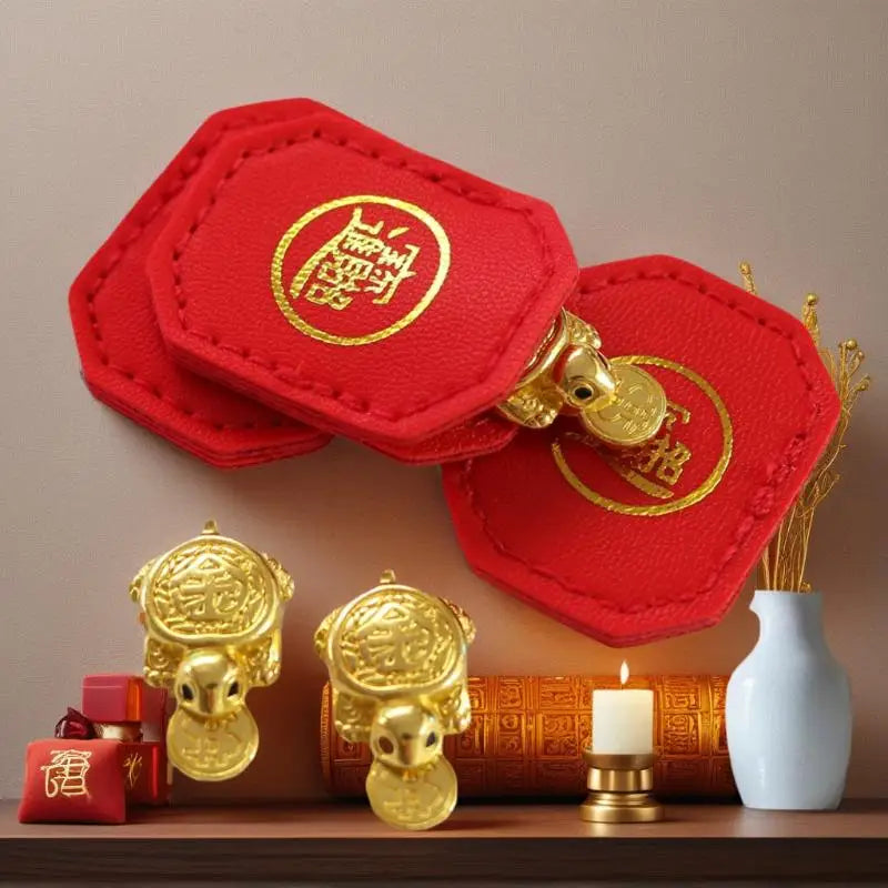 Red felt lucky turtle charms with gold accents displayed on a wooden surface.
