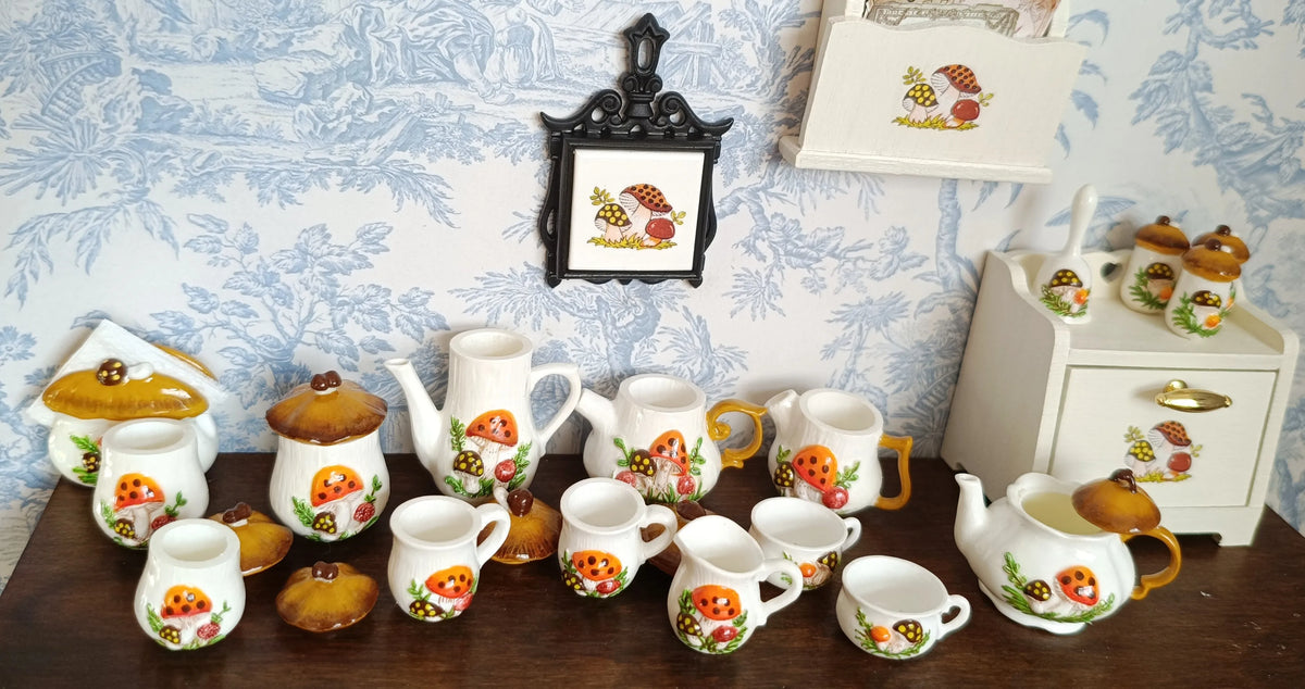 A collection of handcrafted miniature mushroom tableware including cups and saucers displayed on a wooden surface.