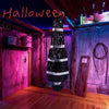 A realistic dead victim prop dressed in black and white stripes stands in a dimly lit, spooky room for Halloween decor.