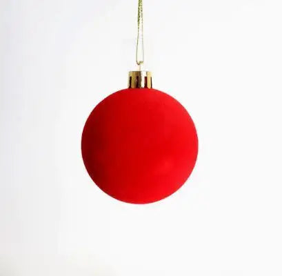 A bright red velvet flocked Christmas tree ornament hanging by a gold string.