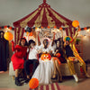 A group of people dressed in horror costumes posing under a large tent arch banner for Halloween