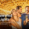 A group of friends enjoying an outdoor party illuminated by warm solar-powered string lights.