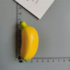 A yellow banana is measured against a ruler, showing its length.