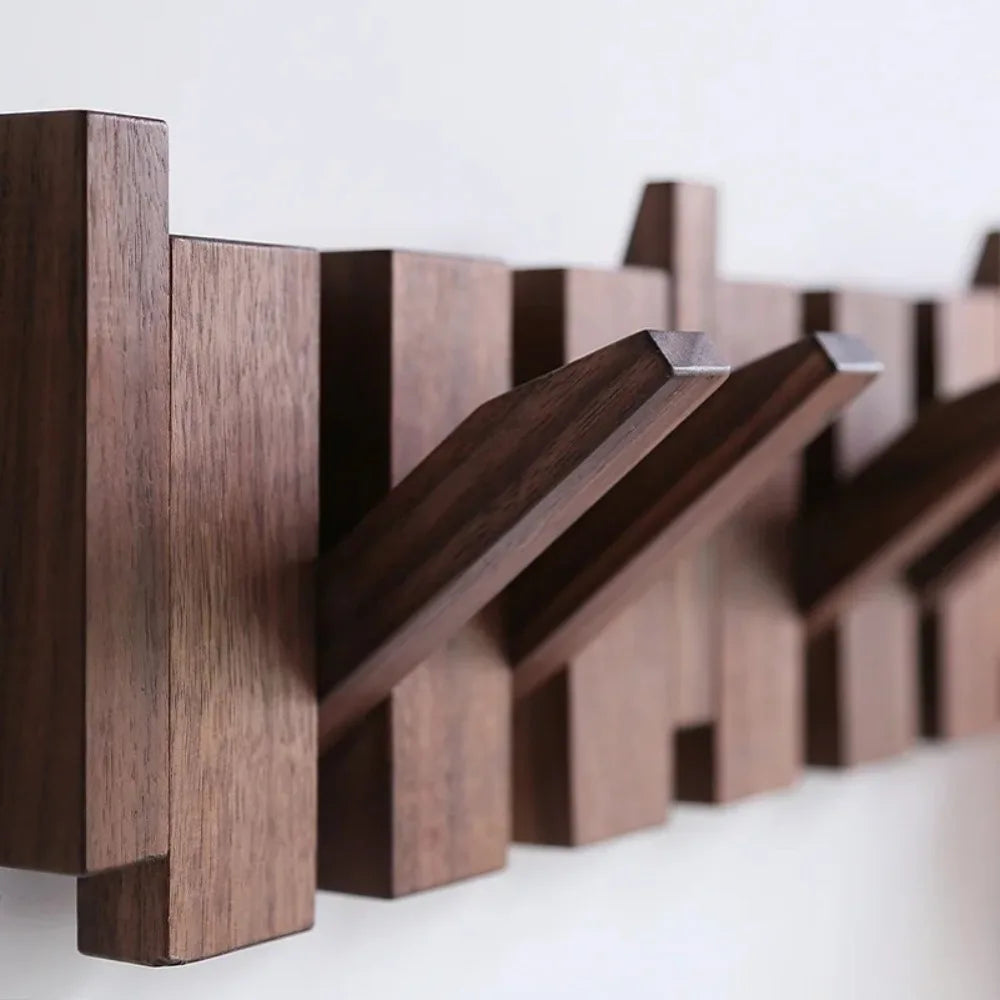 A dark brown wooden wall coat rack featuring eight angled hooks for hanging keys or coats.