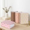 A stack of pink and beige photo albums with gold foil hearts resting on a wooden table.