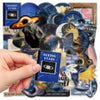 A hand holds a dark blue decal featuring an eye and stars, surrounded by various space-themed astronomy decals.