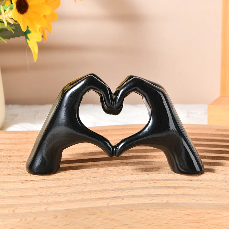 Black heart shape sculpture made of gold-toned material resting on a wooden surface.