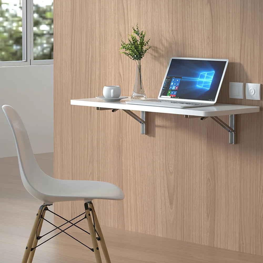 A laptop is placed on a wooden wall shelf bracket mounted on a light wood panel, with a white chair in the foreground.