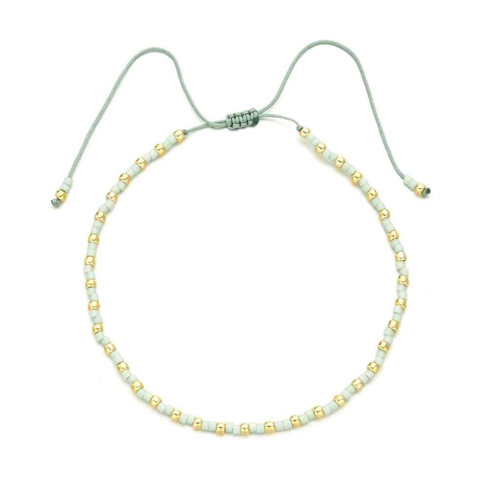 Handmade boho glass bead bracelet with adjustable cord in pale green and gold beads