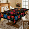 A vibrant Mexican style embroidered tablecloth featuring colorful floral patterns on a wooden dining table.