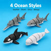 A set of four gray and white articulated ocean animal figurines: sawfish, shark, orca, and beluga.