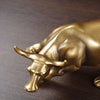 A bronze-colored sculpture of a bull's head and snout resting on a dark wooden surface.