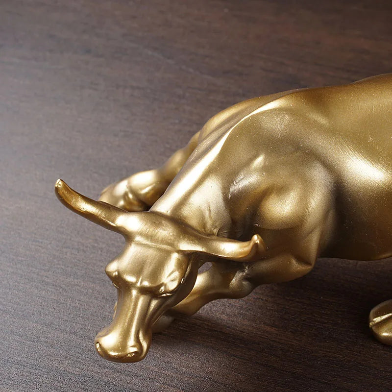 A bronze-colored sculpture of a bull's head and snout resting on a dark wooden surface.