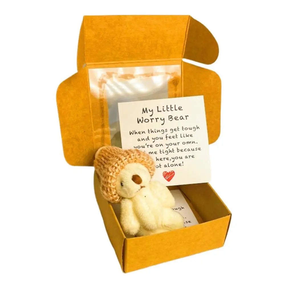 Un pequeño oso de peluche en una caja amarillo-anaranjada con una tarjeta inspiradora dentro