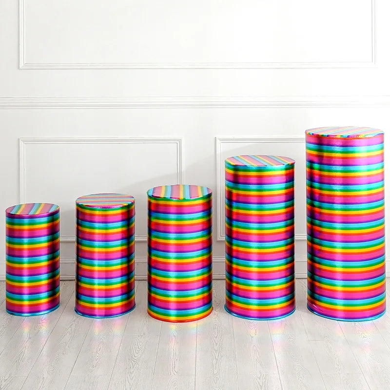 A row of colorful spandex cylinder stands with horizontal stripes in various bright colors on a white floor.