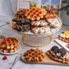 A golden wire stand holds various waffle foods including Belgian waffles, sweet waffles, and waffle slices.