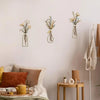 A set of three rustic metal flower wall art pieces displayed on a white wall.
