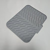 A gray silicone drain mat with parallel ridges and a cutout for a kitchen sink.