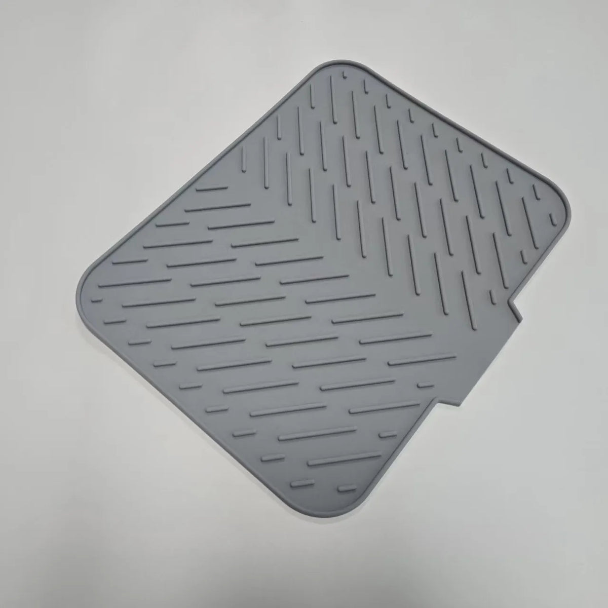A gray silicone drain mat with parallel ridges and a cutout for a kitchen sink.