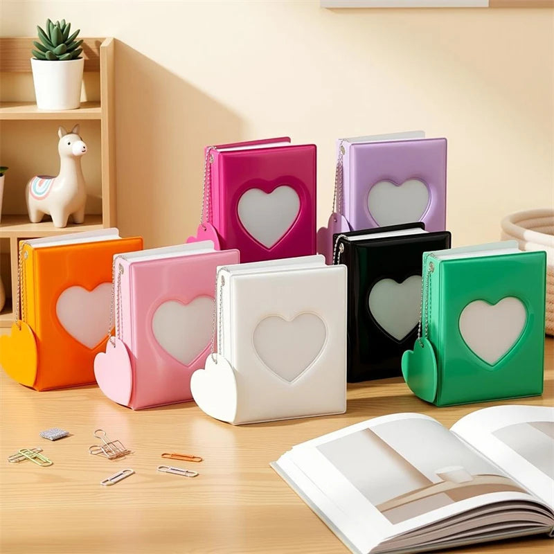 A collection of colorful heart-shaped window photocard albums in pink, purple, orange, and green resting on a wooden surface.
