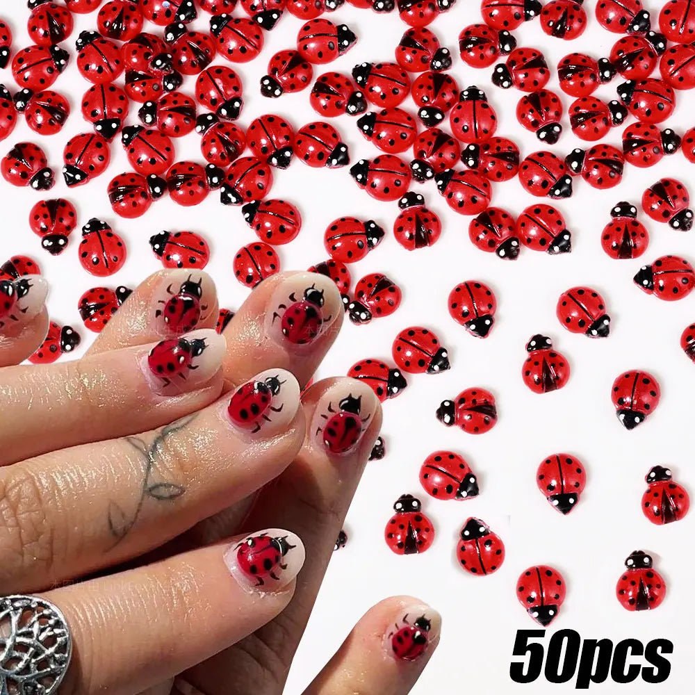 A close-up of a hand displaying 50 small red and black ladybug resin nail art charms.