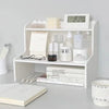 A white two-layer desktop organizer shelf displaying skincare products, a clock, and various stationery items.