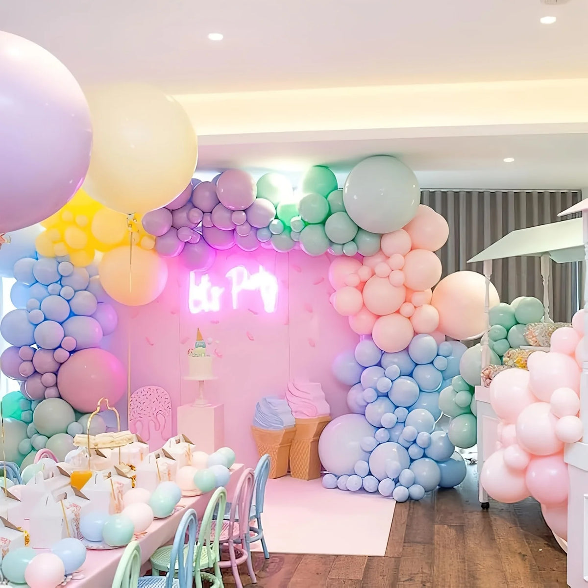 A colorful display of pastel rainbow latex balloons in various shades of pink, purple, yellow, and green for a celebration.