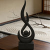 A black, stylized flame sculpture decor made from 3D printed material, displayed on a wooden surface.