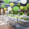 A row of white and lime green decorative paper lanterns hang above a modern seating area with light wood flooring.
