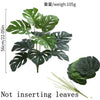A green artificial palm tree with large leaves shown against a white background.