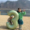 Two children posing with a large vintage number balloon shaped like the number 8 outdoors