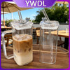 A clear glass insulated coffee mug filled with iced latte, featuring a metal lid and straw, set on a wooden table.