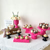 Two pink cupcake stands decorated with flowers and used for party display.