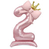 A pink foil balloon shaped like the number 9, decorated with a bow and topped with a gold crown.