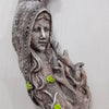 A textured, gray wall hanging featuring a face emerging from tree roots and leaves.