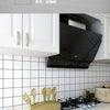 A modern kitchen setup featuring a black range hood and gold utensils mounted on a white tiled backsplash.
