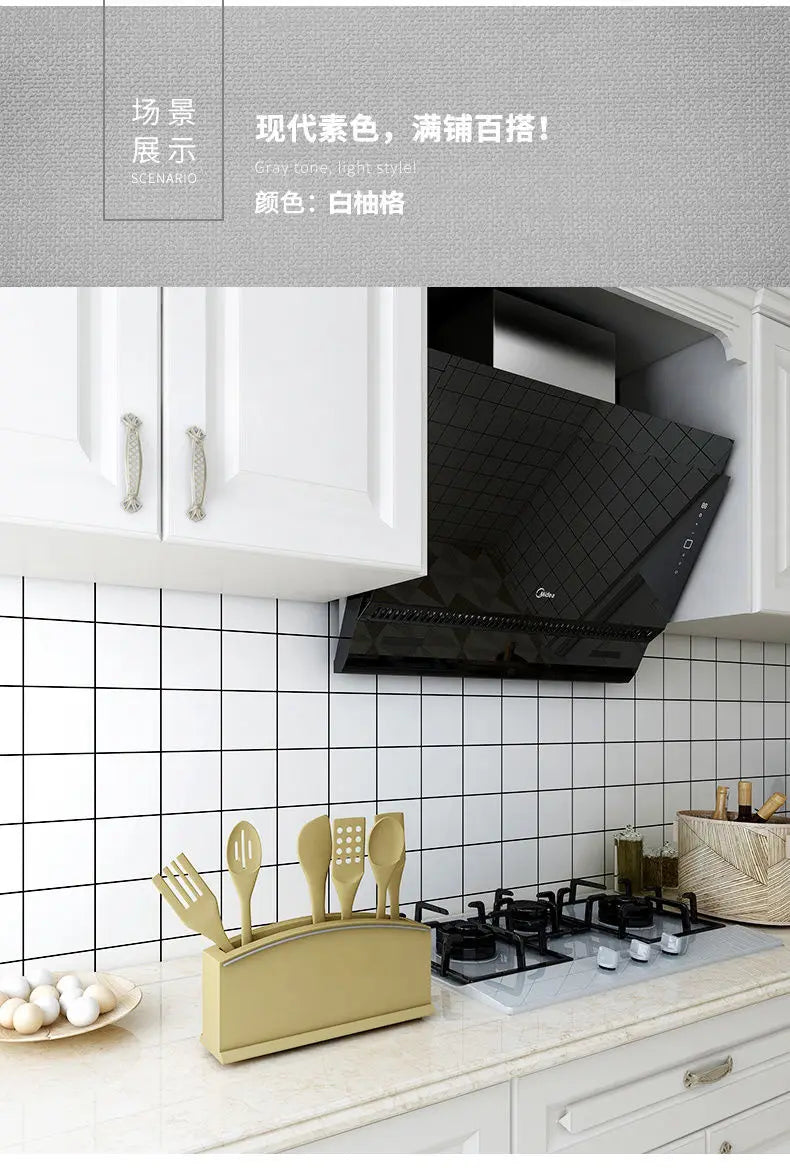 A modern kitchen setup featuring a black range hood and gold utensils mounted on a white tiled backsplash.