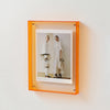 Acrylfoto-Displayrahmen mit orangem Rand, der ein Ganzkörperbild von zwei Models in weißer Kleidung zeigt.