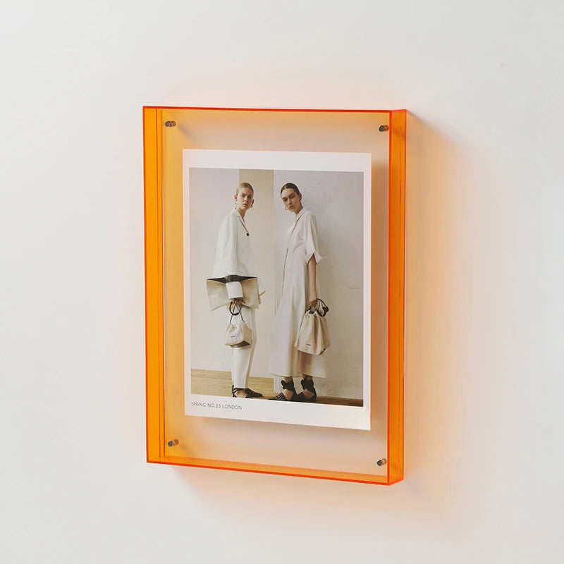 Acrylfoto-Displayrahmen mit orangem Rand, der ein Ganzkörperbild von zwei Models in weißer Kleidung zeigt.