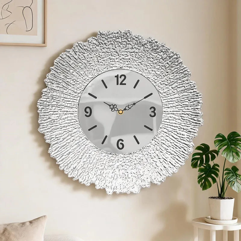 A round white textured wall clock with a silver-toned face and hands hanging on a light-colored wall.
