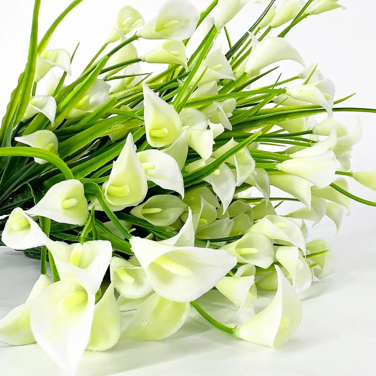 A bouquet of artificial white calla lilies with green stems for home and event decoration.