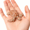 A hand holds a small, brown, 3D printed articulated turtle figurine decoration.