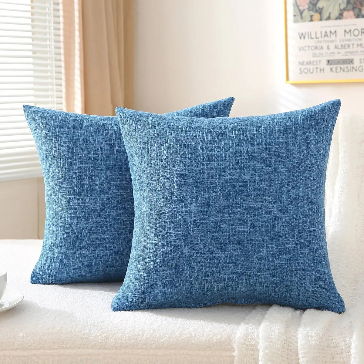 A set of two solid blue linen pillows resting on a white surface.