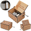 A vintage hand-cranked wooden music box with an ornate lid and decorative carvings, featuring a ballerina silhouette.