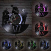 A dark wall display featuring multiple vintage vinyl record-themed clocks and silhouettes against a brick background.