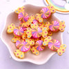 A pile of colorful, swirling candy resin cabochons in pink, yellow, and green hues on a white dish.